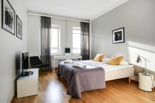 a white bedroom with a bed and a desk at Kotimaailma Apartments Kamppi - 2BR for 4 persons in Helsinki