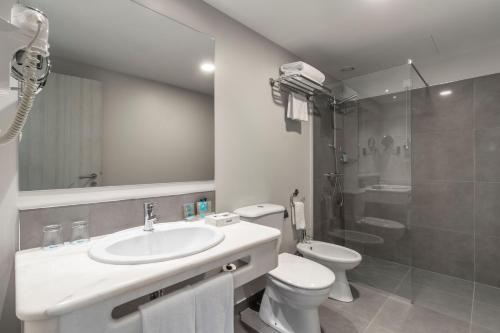 a bathroom with a sink and a toilet and a shower at Enotel Magnólia in Funchal
