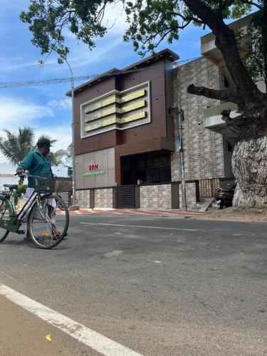 a person riding a bike in front of a building at SAN BEACH RESIDENCY in kāraikāl