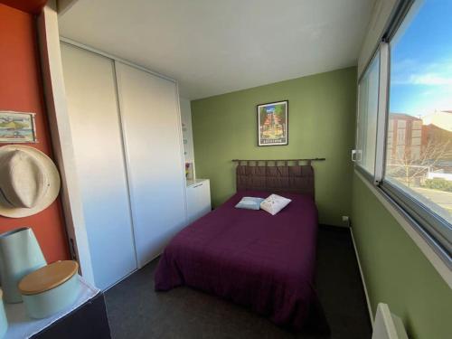 - une petite chambre avec un lit violet et une fenêtre dans l'établissement Appartement dans une résidence avec piscine à Arcachon, à Arcachon