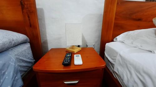 a nightstand with a remote control and a lamp on it at Alma de cedrela in Puerto Ayora