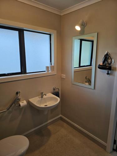 a bathroom with a sink and a toilet and windows at Catlins area accommodation in Owaka
