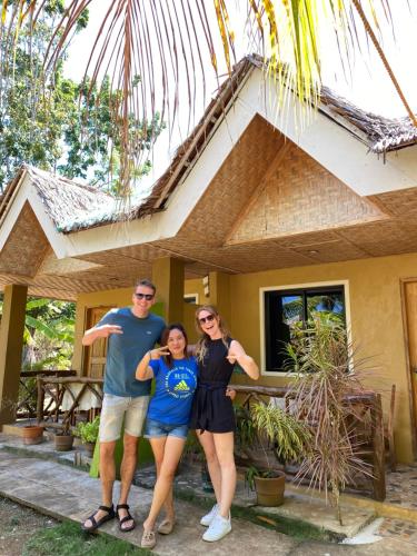 una familia parada frente a una casa en MIKI's Guest House en Siquijor