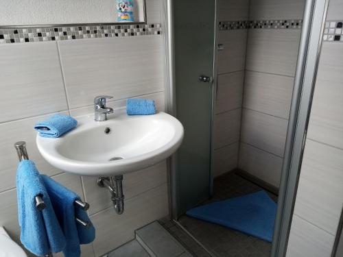 a bathroom with a sink and a shower with blue towels at Ferienwohnung Backbord in Büsumer Deichhausen