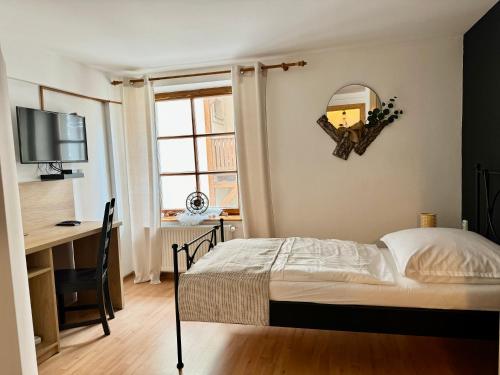 a bedroom with a bed and a desk and a mirror at Schiller Haus&Restaurant in Spišská Belá