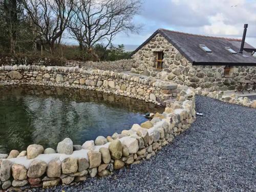 a stone wall around a pond in front of a house at The Bothy in Caernarfon