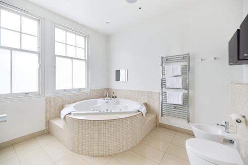 baño con bañera grande y lavamanos en The Clapham Crib - Spacious 4BDR House with Patio en Londres