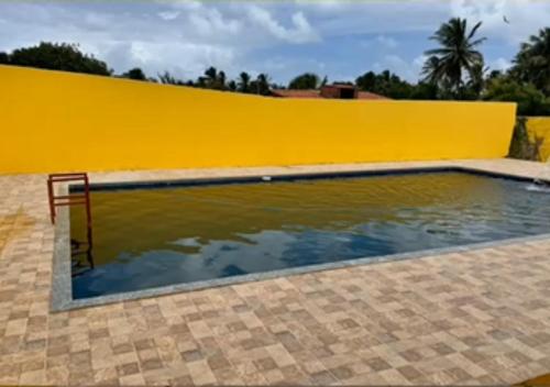 uma piscina em frente a uma parede amarela em Casa na em moitas de Amontada em Praia de Moitas