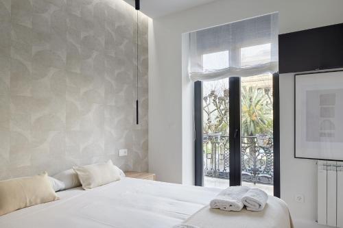 een slaapkamer met een wit bed en een raam bij The Rentals Collection - Opera in San Sebastian