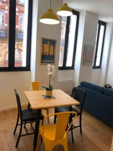 - une salle à manger avec une table, des chaises et un canapé bleu dans l'établissement Le T2 Capitole - Hypercentre - Metro - Wifi, à Toulouse