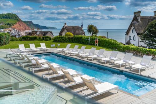 een zwembad met ligstoelen en een zwembad bij Harbour Hotel & Spa Sidmouth in Sidmouth