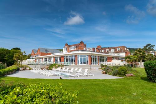 ein großes Gebäude mit weißen Stühlen davor in der Unterkunft Harbour Hotel & Spa Sidmouth in Sidmouth