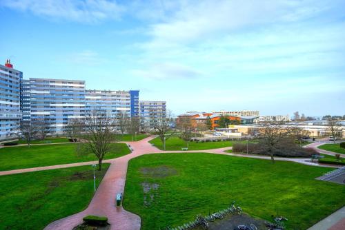 ein Park mit einer Bank, Gras und Gebäuden in der Unterkunft Ferienpark - Haus N, App 0N0301 in Heiligenhafen