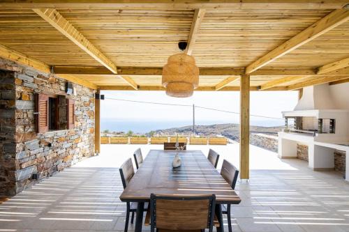 an outdoor dining room with a wooden table and chairs at Kea 360 VILLAS- Dionysos Den in Korissia
