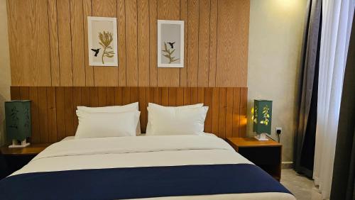 een slaapkamer met een bed en twee foto's aan de muur bij Grik Hotel - Entebbe in Entebbe