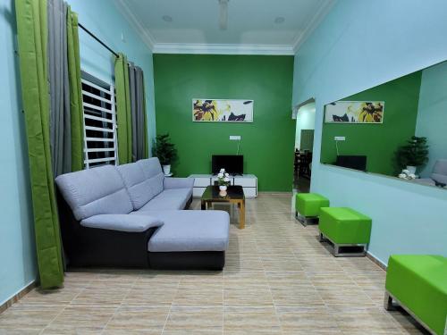 - un salon avec un canapé et des murs verts dans l'établissement Nipah Homestay Kuala Besut, à Kampung Kuala Besut