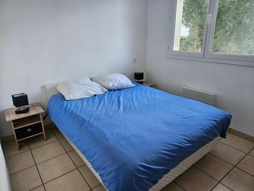 une chambre avec un lit avec des draps bleus et une fenêtre dans l'établissement Soustons - Piscine - Famille - Centre Ville, à Soustons