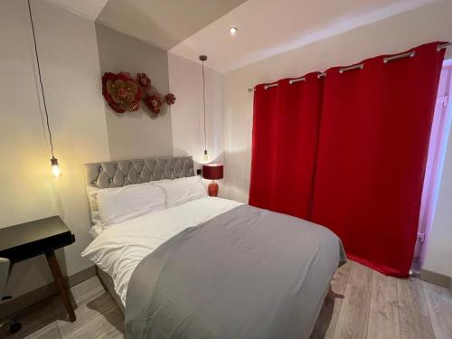 a bedroom with a bed with a red curtain at Letzi private en-suite Near Wembley in London