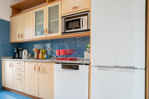 a kitchen with wooden cabinets and a white refrigerator at Forum Madeira Ajuda Apartment in Funchal