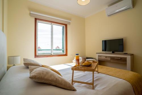 a bedroom with a bed with a table and a television at Forum Madeira Ajuda Apartment in Funchal