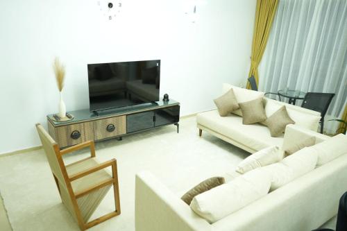 a living room with two white couches and a television at Curve Hostel JBR in Dubai