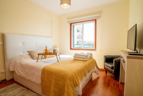a bedroom with a bed with a table and a television at Forum Madeira Ajuda Apartment in Funchal