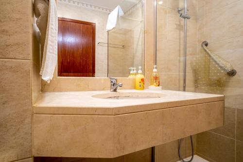 a bathroom with a sink and a shower at Forum Madeira Ajuda Apartment in Funchal
