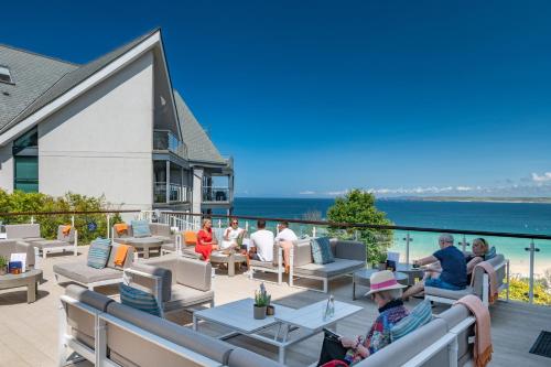 a group of people sitting on a patio overlooking the ocean at Harbour Hotel & Spa St Ives in St Ives