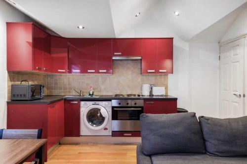 a kitchen with red cabinets and a washing machine at New Soho Loft - Apt 3 by Indigo Flats in London