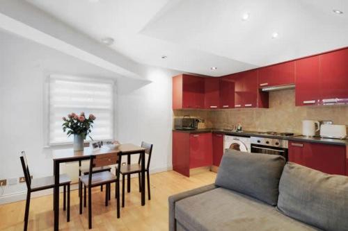 a kitchen with red cabinets and a table and a couch at New Soho Loft - Apt 3 by Indigo Flats in London