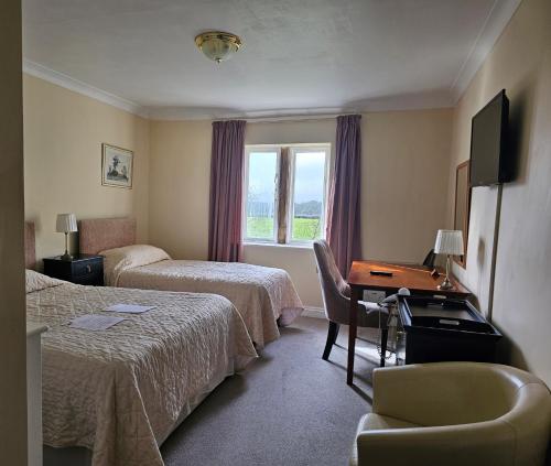 a hotel room with two beds and a desk and a window at Schoolhouse Restaurant and Hotel in Swindon