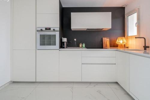 Il comprend une cuisine avec des placards blancs et une télévision murale. dans l'établissement Marina Victoria, au Cap d'Agde