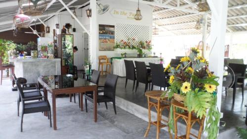 a dining room with tables and chairs and flowers at The Hip Resort @ Khao Lak in Bang Sak