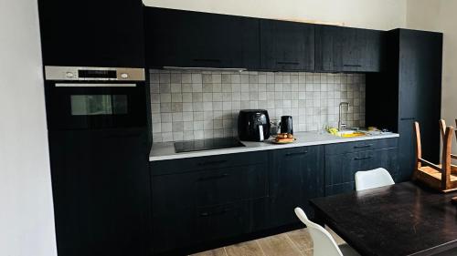 eine schwarze Küche mit schwarzen Schränken und einem Tisch in der Unterkunft Vakantiehuis De Zwaan in Benk en Donk