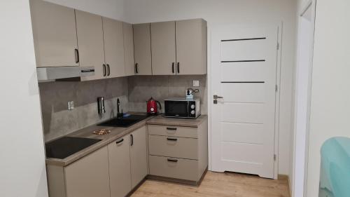 kuchnia z białymi szafkami, zlewem i kuchenką mikrofalową w obiekcie Apartamenty Centrum Plac Wolności ApartHotel w Kielcach