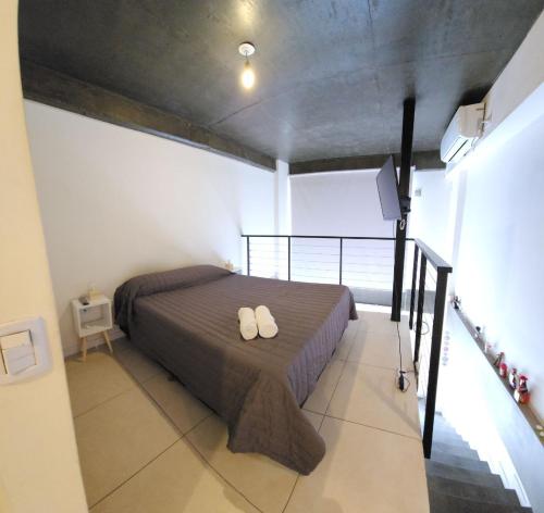 Un dormitorio con una cama con dos zapatos blancos. en Casita de Tucumán - Loft San Martin en San Miguel de Tucumán