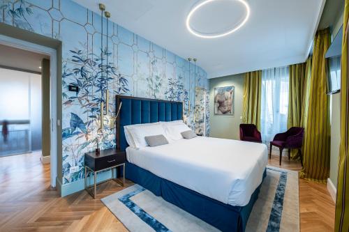 1 dormitorio con 1 cama grande y pared azul en Glimpse Hotel, en Florencia
