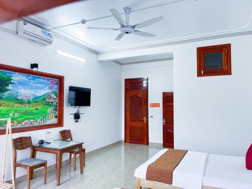 Schlafzimmer mit einem Bett, einem Tisch und einem TV in der Unterkunft HagiangGo Hostel-Motorbikes rental and Tour in Ha Giang