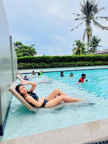 a woman laying in a chair in a swimming pool at Sunsets and Good Vibes - 2 Bedroom Condo Unit in Iloilo City