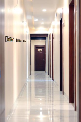korytarz z białymi ścianami i ciemnobrązowymi drzwiami w obiekcie Hotel Jayesh Inn w mieście Pusad