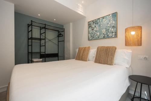 a bedroom with a white bed and a mirror at Apartamentos 7 dreams in Málaga