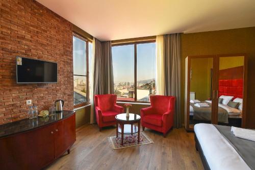 トビリシにあるKraveli Hotelのベッド1台と赤い椅子2脚が備わるホテルルームです。