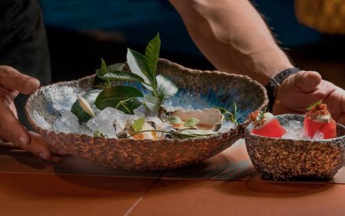 a person holding two bowls of food on a table at Aguas de Ibiza Grand Luxe Hotel - Small Luxury Hotel of the World in Santa Eularia des Riu