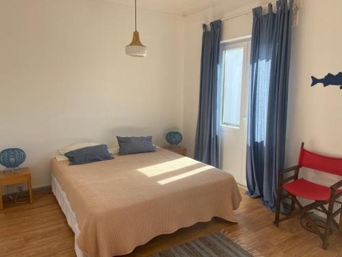 a bedroom with a bed and a red chair at Eskama hostel in Esposende