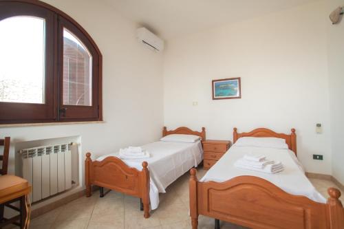 two beds in a room with a window at Dammuso Ignazio in Lampedusa