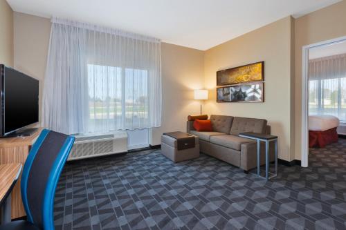 a hotel room with a couch and a television at TownePlace Suites by Marriott Grand Rapids Airport Southeast in Grand Rapids