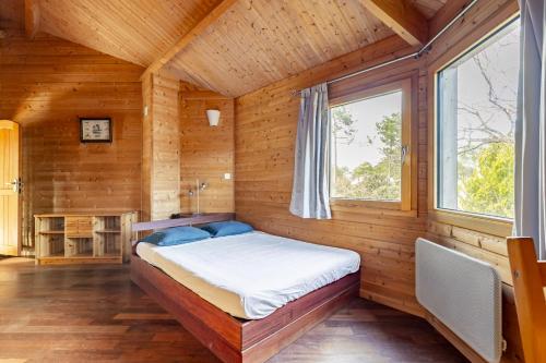 une chambre avec un lit dans une cabane en bois dans l'établissement Villa 5ch au calme dans le domaine du golf, à Lacanau
