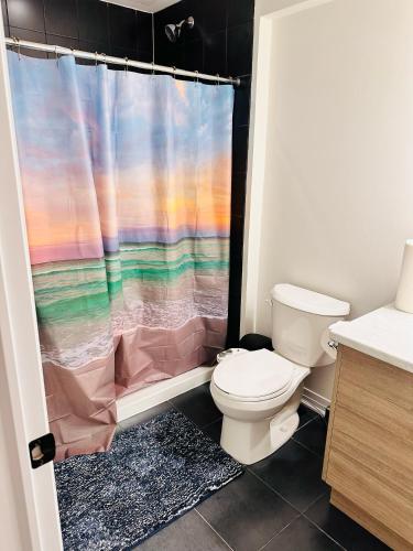 a bathroom with a toilet and a shower curtain at Private and spacious Basement in Kitchener