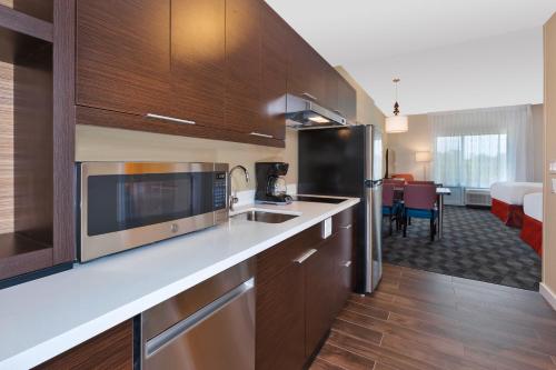 a kitchen with wooden cabinets and stainless steel appliances at TownePlace Suites by Marriott Grand Rapids Airport Southeast in Grand Rapids