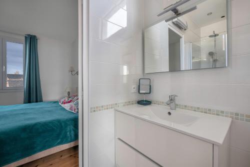 a bathroom with a sink and a mirror and a bed at Parenthèse en famille et détente au Pouliguen in Le Pouliguen